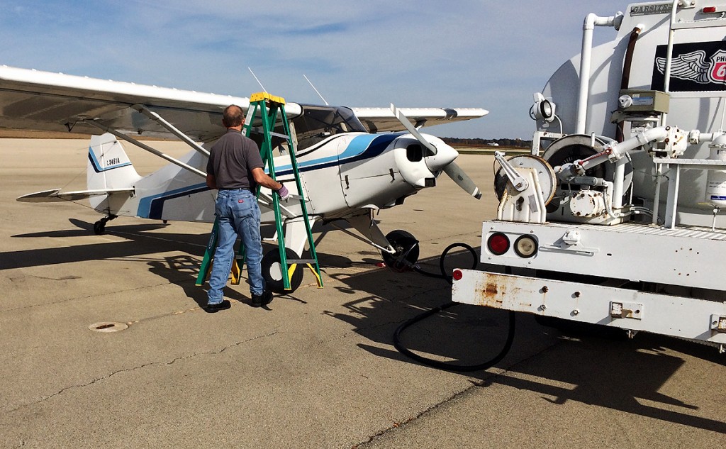 man places refueling ladder in front of aircraft wing