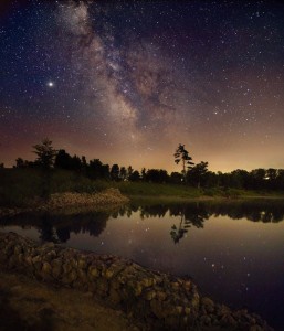 Milky Way in night sky above a lake shore