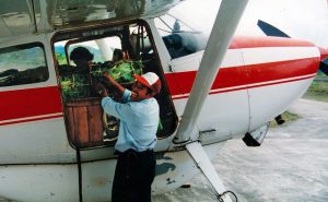 Smiling man loading cargo into a single engine airplane