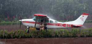 Children huddled under airplane wing in jungle rain that blocks the true light